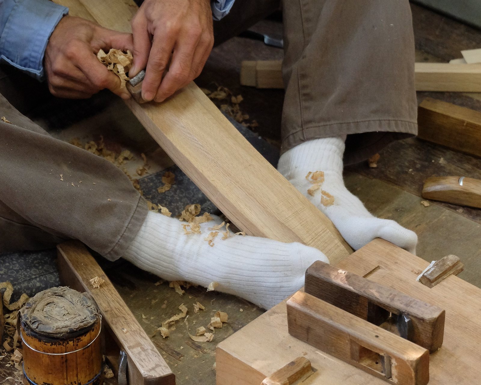 A craftsman planing a length of wood by hand in the workshop