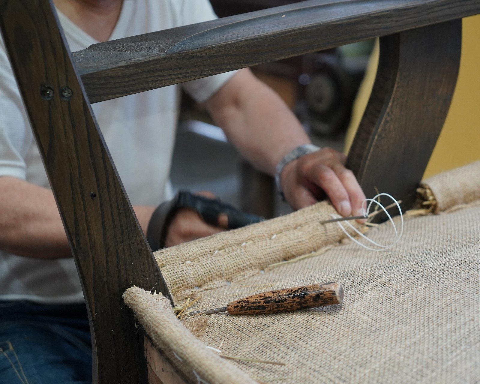 A craftsman working on the upholstery of a chair seat