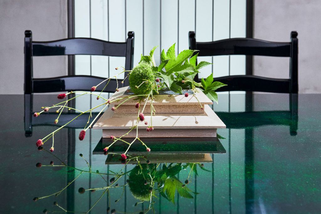 Close view of the lacquered tabletop reflecting a floral arrangement