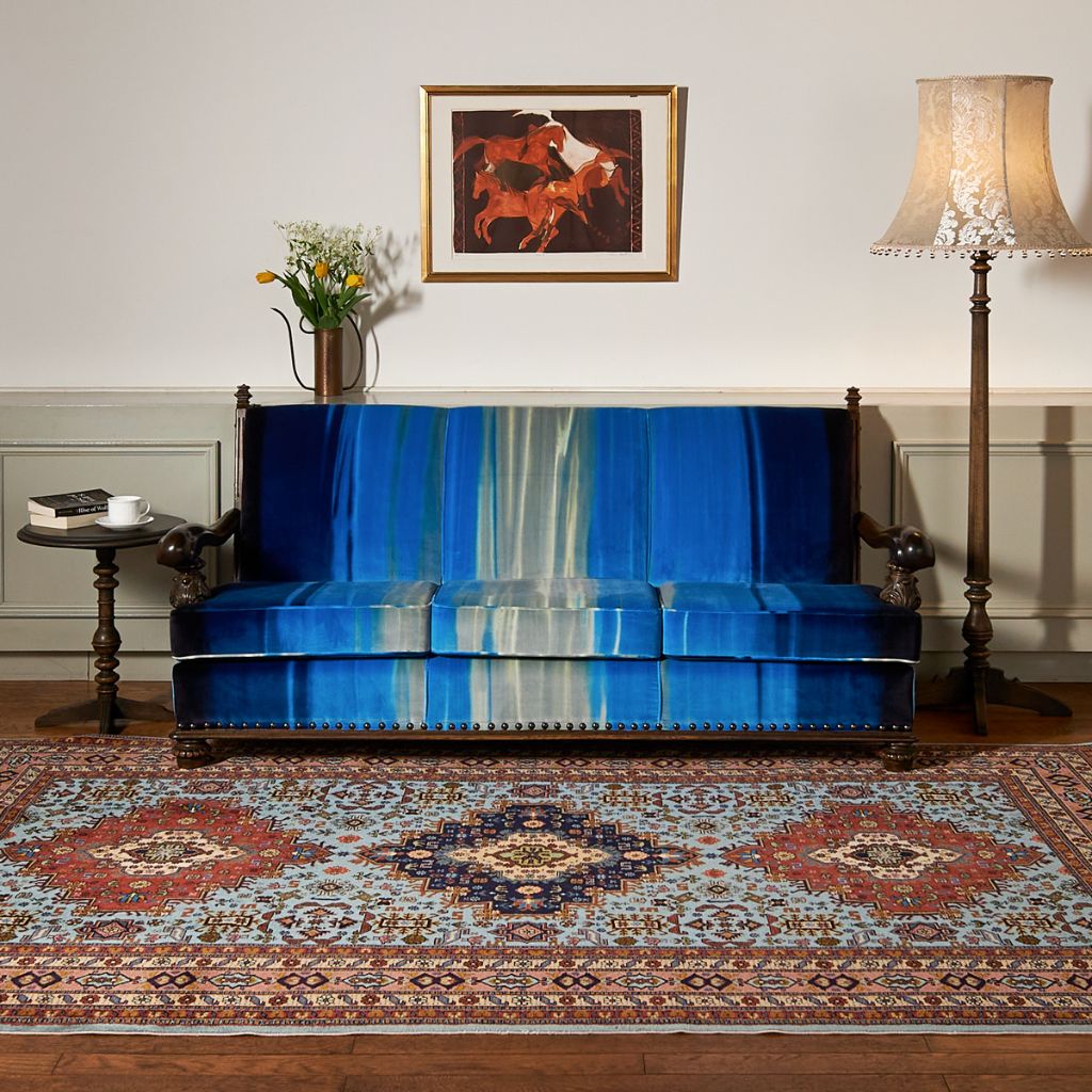 Genkotsu Sofa upholstered in blue fabric, on a patterned rug beside a floor lamp