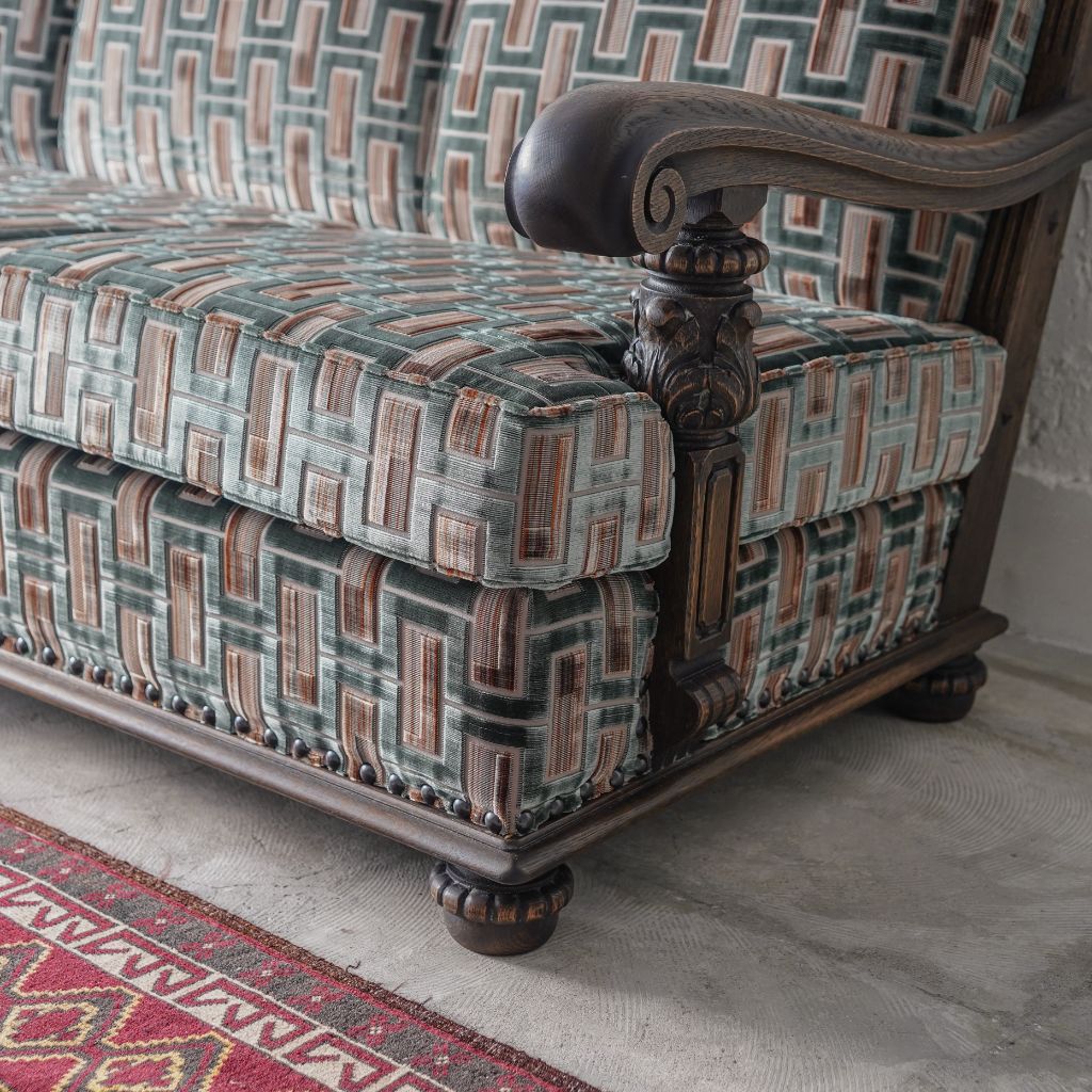 Detail of a carved wooden sofa arm and patterned upholstery