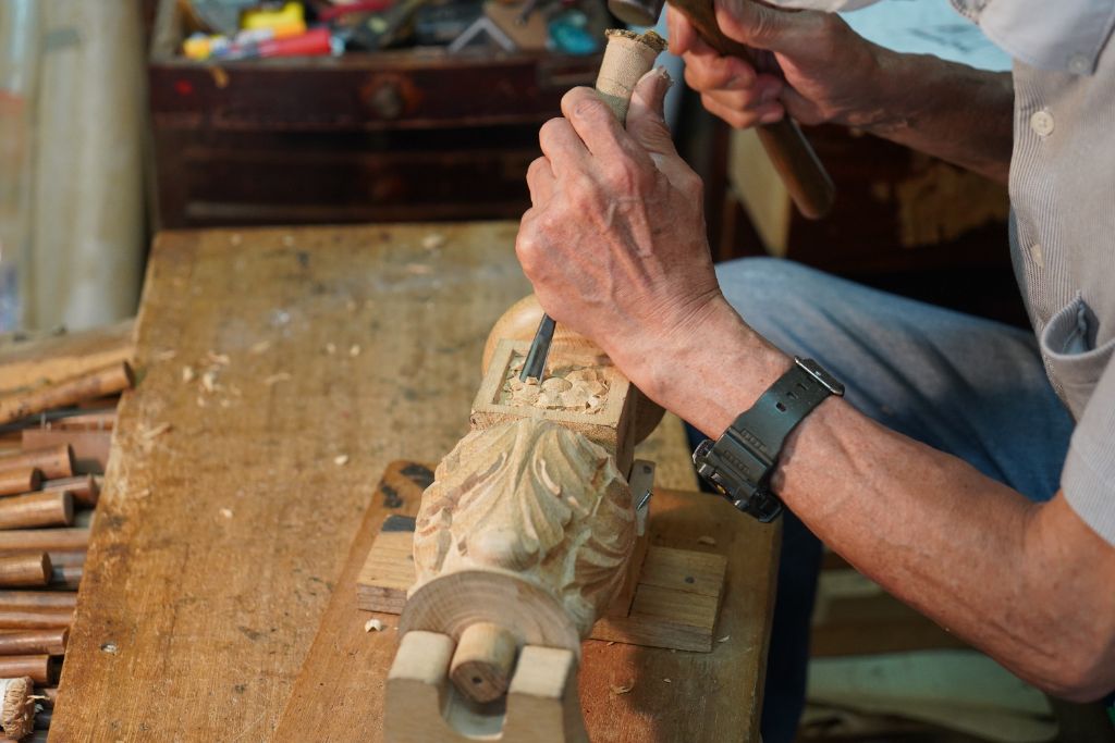 A craftsman carving a wooden furniture part by hand