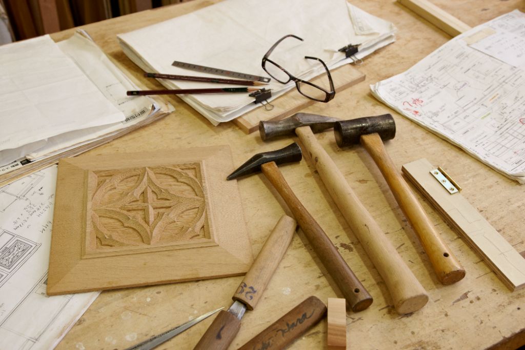 Woodworking tools and a carved panel laid out on a workbench